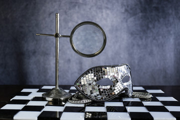 Maschera d'argento sopra la scacchiera bianca e nera ,la festa dei coriandoli e cristalli