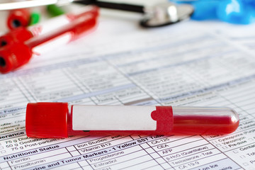 Red blood vial with blood sample over test form background.