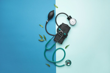 Stethoscope with sphygmomanometer on color background