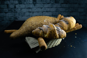 Different kinds of fresh bread with grain on black rustic background.