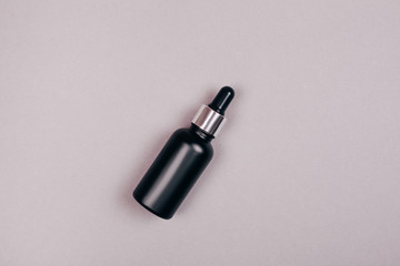 Matte black oil bottle cosmetics. Flat lay style.