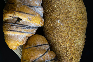 Different kinds of fresh bread with grain on black rustic background.
