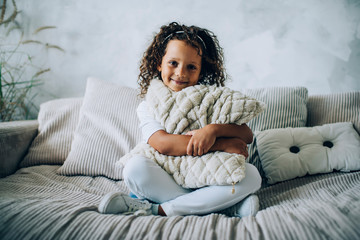 Charming kid with pillow on home couch
