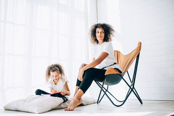 African American daughter and mother sitting next to each other in room