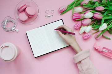 Girl writing wish list of future plans. flat lay composition with flowers, a notepad, cup of coffee...