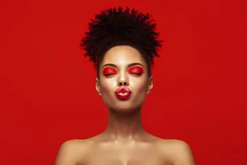 Lippen küssen. Liebe teilen. Valentinstag. Afrikanisches Make-up-Gesicht. Zufriedene junge Frau des Brunette mit Afrofrisur gegen bunten Hintergrund. © Beauty Agent Studio