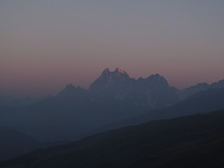 Mountain landscape of Svaneti on bright summer sunny day. Mountain lake, hills covered green grass on snowy rocky mountains background. Caucasus peaks in Georgia. Amazing view on wild georgian nature