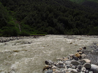 Mountain landscape of Svaneti on bright summer sunny day. Mountain lake, hills covered green grass on snowy rocky mountains background. Caucasus peaks in Georgia. Amazing view on wild georgian nature