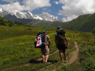 Mountain landscape of Svaneti on bright summer sunny day. Mountain lake, hills covered green grass on snowy rocky mountains background. Caucasus peaks in Georgia. Amazing view on wild georgian nature