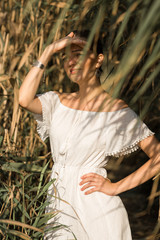 Portrait of a young beautiful girl in reeds in retro style in a light dress.