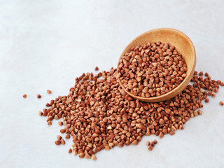 Raw buckwheat grains in wooden bowl (Fagopyrum esculentum)