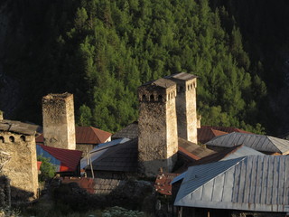 Mountain landscape of Svaneti on bright summer sunny day. Mountain lake, hills covered green grass on snowy rocky mountains background. Caucasus peaks in Georgia. Amazing view on wild georgian nature