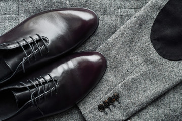 Close of fashionble men dark red leather shoes on tweed fabric background. 