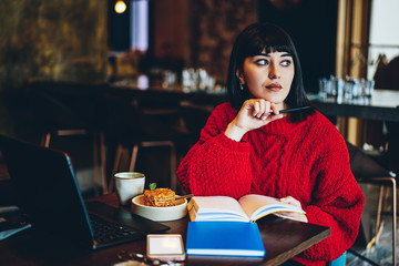 Pensive woman with gadgets and notepad in restaurant