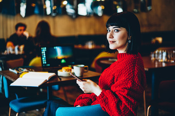 Satisfied charming female using phone in cafe