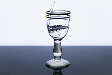 Shot glass of cold vodka on a beautiful background. Vodka poured into a shot glass