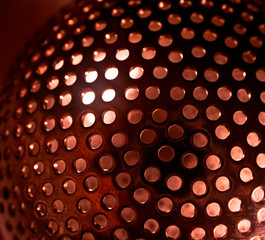 Metal sphere with holes and light iside. Perforated surface background