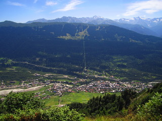 Mountain landscape of Svaneti on bright summer sunny day. Mountain lake, hills covered green grass on snowy rocky mountains background. Caucasus peaks in Georgia. Amazing view on wild georgian nature