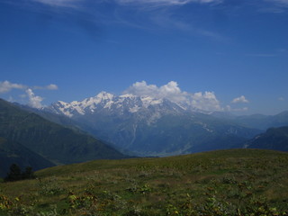 Naklejka premium Mountain landscape of Svaneti on bright summer sunny day. Mountain lake, hills covered green grass on snowy rocky mountains background. Caucasus peaks in Georgia. Amazing view on wild georgian nature