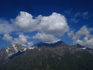 Mountain landscape of Svaneti on bright summer sunny day. Mountain lake, hills covered green grass on snowy rocky mountains background. Caucasus peaks in Georgia. Amazing view on wild georgian nature