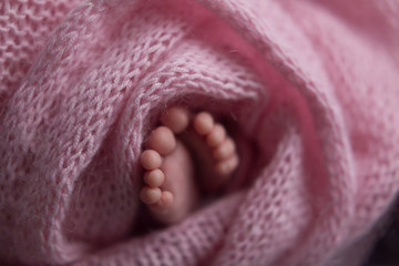 Little baby arms and legs.Baby in a basket on faux fur pink, soft focus