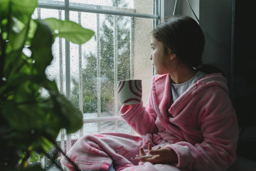 Ill sad child sitting by the window. Health care concept