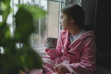 Ill sad child sitting by the window. Health care concept