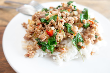 Rice topped with stir-fried pork and basil in a white dish. (Front focus)