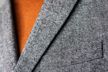 Close up of mens grey wool blazer combined with brown fashionable sweater.  Low DOF. Selective focus.