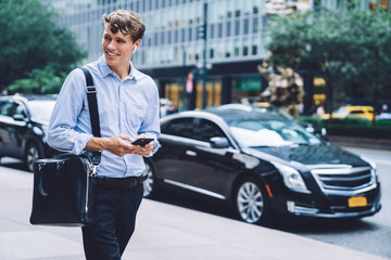 Cheerful Caucasian male trader with trendy briefcase walking to corporate enterprise and enjoying...
