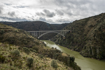 Fototapeta na wymiar Photography of the area known as the Arribes del Duero in Zamora, Spain. The metal arch bridge known as Puente Requejo is seen