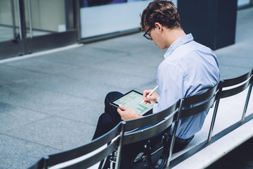 Man sitting on bench and browsing tablet
