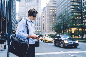 Formally dressed male owner with cellphone listening audio record from motivation seminar via...