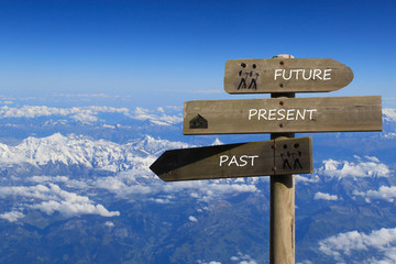 three signs indicating the way to the past, present and future over the mountains
