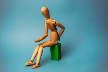 Wooden figure sitting on a green chair. Concept of the problem with digestion. Dysentery