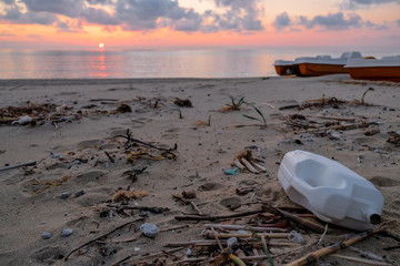 Plastic container trash on wild sea coast, sunset time,pollution cilento italy 