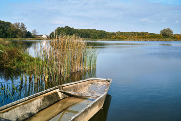 old rowing boat in the reeds on the lake during autumn in Poland.