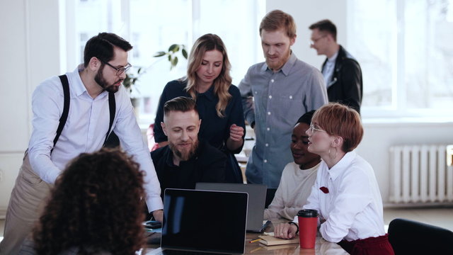 Happy multiethnic smiling colleagues work together, discuss project at loft office brainstorming conference meeting.