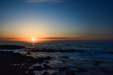 水平線に沈む夕陽と波