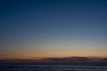 静かな海の夕暮れと三日月