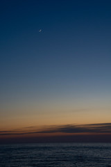 静かな海の夕暮れと三日月