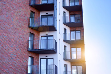 Modern multi story building being lit by the setting sun at afternoon. New apartment house residential building outdoor concept.