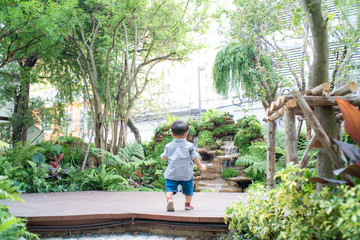 Naklejka na ściany i meble Adorable baby boy toddler walking in garden hpme green tree