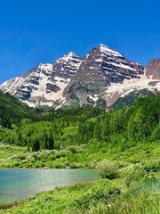 Maroon Bells mountain range turquoise lake and evergreen pine trees and aspens at Maroon Bell Scenic Recreation Area, near Aspen Highlands Ski Area, Colorado Rockies