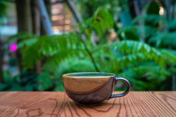 Hot matcha green tea l;atte art on wooden table