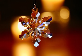 Sparkling crystal snowflake with candle light in background