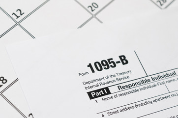 IRS Form 1095-B Health Coverage tax blank lies on empty calendar page