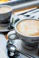 Taza de café con leche con otra taza al fondo
