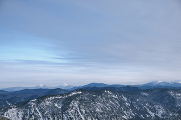 Fototapeta na wymiar Winter mountain landscape.Snow mountains overgrown with taiga against a blue sky. Top view. Russia. Altai Republic.