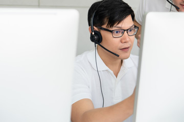 business background of asian male customer service agent on telephone service to customers at...